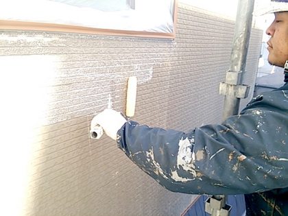 目止め作業中の外壁とダイヤモンドコート外壁塗装認定店の功栄の職人